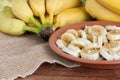Organic bunch of ripe yellow bananas. Pieces cut on a plate with honey and oats. Isolated with blurred green background.Copy space Royalty Free Stock Photo
