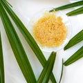 Organic Carnauba Wax in Chemical Watch Glass and broadleaf lady palm leaves on white laboratory table. Top View