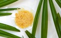 Organic Carnauba Wax in Chemical Watch Glass and broadleaf lady palm leaves on white laboratory table. Top View