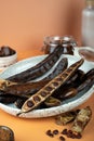 Organic carob pods, seeds in a ceramic plate on a beige background, locust bean healthy food, Ceratonia siliqua harnup. Natural Royalty Free Stock Photo