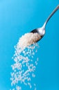 Organic Cereal Grains. Raw Rice Seeds Falling from the Spoon on Blue Background Royalty Free Stock Photo