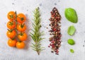 Organic Cherry Orange Rapture Tomatoes on the Vine with basil and pepper on white kitchen background. Fresh rosemary