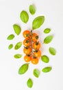 Organic Cherry Orange Rapture Tomatoes on the Vine with basil and pepper on white kitchen background