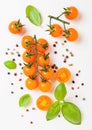 Organic Cherry Orange Rapture Tomatoes on the Vine with basil and pepper on white kitchen background