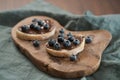 Organic chocolate hazelnut spread with fresh blueberries on ciabatta slices on wood board