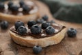 Organic chocolate hazelnut spread with fresh blueberries on ciabatta slices on wood board