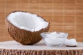 Organic coconut oil in a glass bowl and coconut on natural brown background Royalty Free Stock Photo