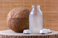 Organic coconut water in a glass jar and coconut on natural background