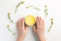 Organic cosmetic concept. Female hands, flowers of calendula and jar of skin care cream Royalty Free Stock Photo