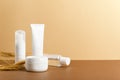 Organic cosmetic white packages with wheat ears composition. Natural skincare products unbranded plastic bottles on beige