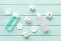 Facial tonic, lotion and cotton pads for face care on mint green wooden background top view mock up