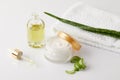 organic cream and perfume, pipette, towel and aloe vera slices and leaf on white surface