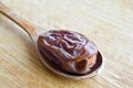 Organic dried hurma dates medjool grains, in wooden spoon on cutting board