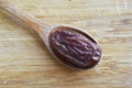 Organic dried hurma dates medjool grains, in wooden spoon on cutting board