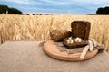 Organic food - bread lying on the table, against the background of a wheat field. Agricultural with food background Royalty Free Stock Photo