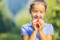 Cropped portrait of hungry female kid is ready to taste an autumnal apple, enjoying annual harvest in apple-trees garden