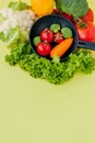 Organic food. Healthy vegetables with broccoli, lettuce, red and yellow sweet pepper, cucumber on a black skillet. Top view. Vegan Royalty Free Stock Photo