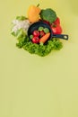 Organic food. Healthy vegetables with broccoli, lettuce, red and yellow sweet pepper, cucumber on a black skillet. Top view. Vegan Royalty Free Stock Photo