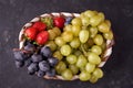 Organic fresh berries of green grapes, strawberries, raspberries, blue blueberries in a basket on a dark concrete background. Royalty Free Stock Photo