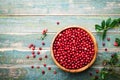 Organic fresh cowberry lingonberry, partridgeberry, foxberry in wooden bowl on rustic vintage table top view.