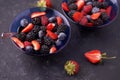 Organic fresh ripe blackberries, strawberries, raspberries, blueberries in blue saucers on a dark concrete background. Royalty Free Stock Photo