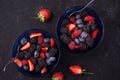 Organic fresh ripe blackberries, strawberries, raspberries, blueberries in blue saucers on a dark concrete background. Royalty Free Stock Photo