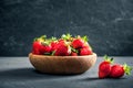 Organic fresh ripe strawberry in a wooden bowl on a dark background. Healthy fruits and berry, vegaterian food