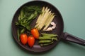 Organic fresh vegetables courgette, tomato, asparagus, basil, dill, green peas, garlic in a frying pan Royalty Free Stock Photo