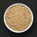 Organic green lentils in a white bowl on a black background, top view. Flat lay, overhead, from above. Close-up Royalty Free Stock Photo