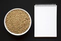 Organic green lentils in a white bowl, blank notepad on a black background, overhead view. Flat lay, top view, from above. Copy Royalty Free Stock Photo