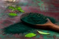 Organic green spirulina powder top view on wooden spoon background. Super foods,