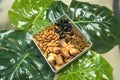 Organic healthy food in bowl on tropical leaves,different dry fruits almonds dates dry black raisins