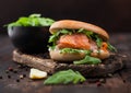 Organic healthy sandwich with salmon and bagel, cream cheese and wild rocket on wooden board