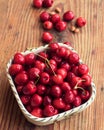 Organic homegrown cherries and stones in a vintage ceramic bowl, on wooden background