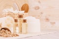 Organic homemade white cosmetics, bottles with oil and raw oatmeal flakes, bath accessories on light beige wooden background. Royalty Free Stock Photo