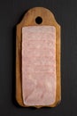 Organic Jamon Cocido Extra on a rustic wooden board on a black background, top view. Flat lay, overhead, from above