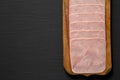 Organic Jamon Cocido Extra on a rustic wooden board on a black background, top view. Flat lay, overhead, from above. Copy space