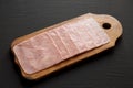 Organic Jamon Cocido Extra on a rustic wooden board on a black surface, side view