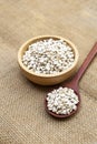 Organic Job`s tears seed in round wooden bowl and wooden spoon on hessian fabric background