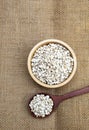 Organic Job`s tears seed in wooden bowl and wooden spoon display on hessian fabric texture
