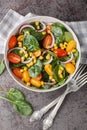 Organic low calorie salad of fresh spinach, corn, cherry tomatoes and red onion with olive oil dressing close up in a bowl on the