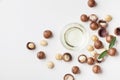 Organic macadamia oil and heap of nuts on white table top view. Royalty Free Stock Photo