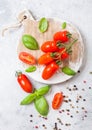 Organic Mini San Marzano Tomatoes on the Vine with basil and pepper on chopping board on white kitchen background