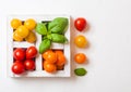 Organic Mini Tomatoes with basil and pepper in wooden box on stone kitchen background. San Marzano, orange and cherry tomatoes Royalty Free Stock Photo