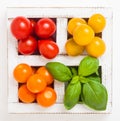 Organic Mini Tomatoes with basil and pepper in wooden box on stone kitchen background. San Marzano, orange and cherry tomatoes Royalty Free Stock Photo