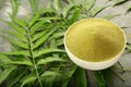 Organic neem leaves powder in ceramic bowl.