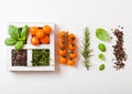 Organic Orange Rapture Cherry with basil and pepper and rosemary in white wooden box on stone kitchen background. Cooking concept