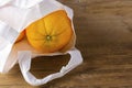 Organic orange in white fabtic bag on wooden textured surface with knife. Buying imperfect product to reduce food waste