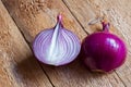 Organic peeled halved red onion bulb with water drops on weathered wood table. Rustic kitchen interior. Healthy food ingredients Royalty Free Stock Photo