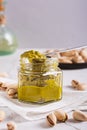Organic pistachio spread cream in a jar and nuts on a plate on the table vertical view Royalty Free Stock Photo